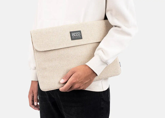 A man carrying his laptop in a beige hemp laptop case.